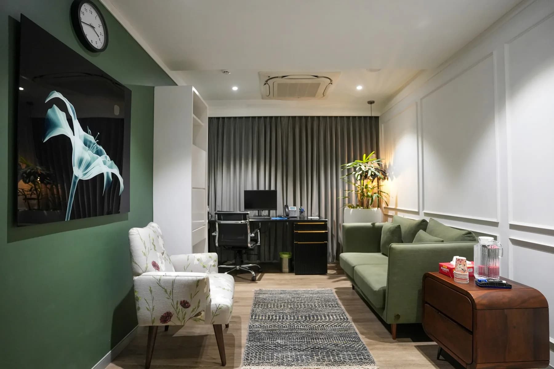 A consulting room with a deep green accent wall and desk