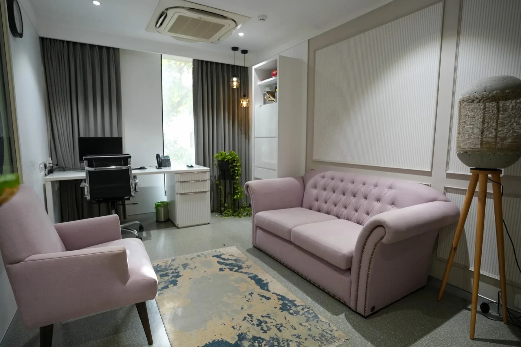 A blush consulting room with a two-seater sofa and desk