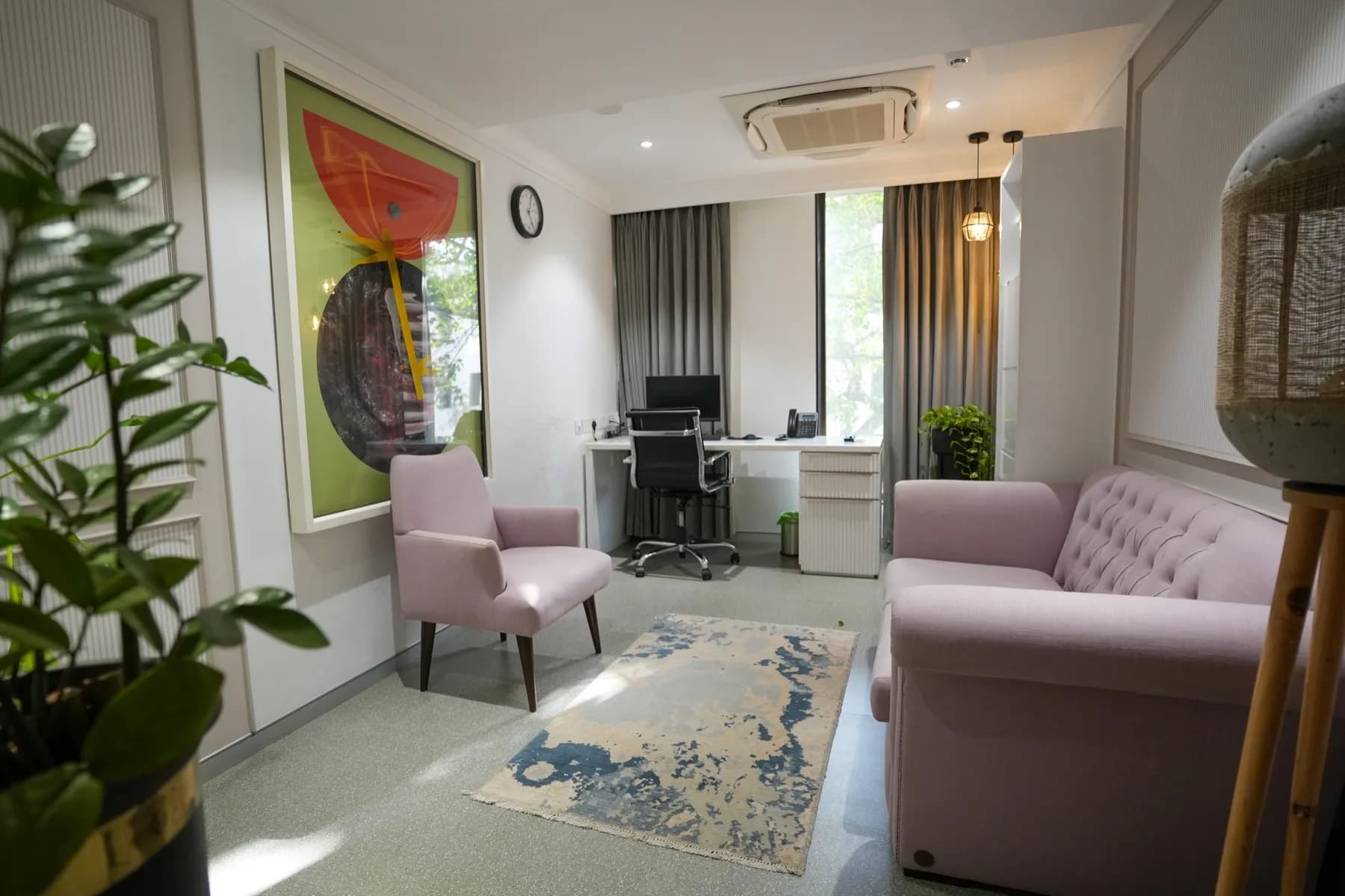 A therapy room with artwork, plants and a corner desk