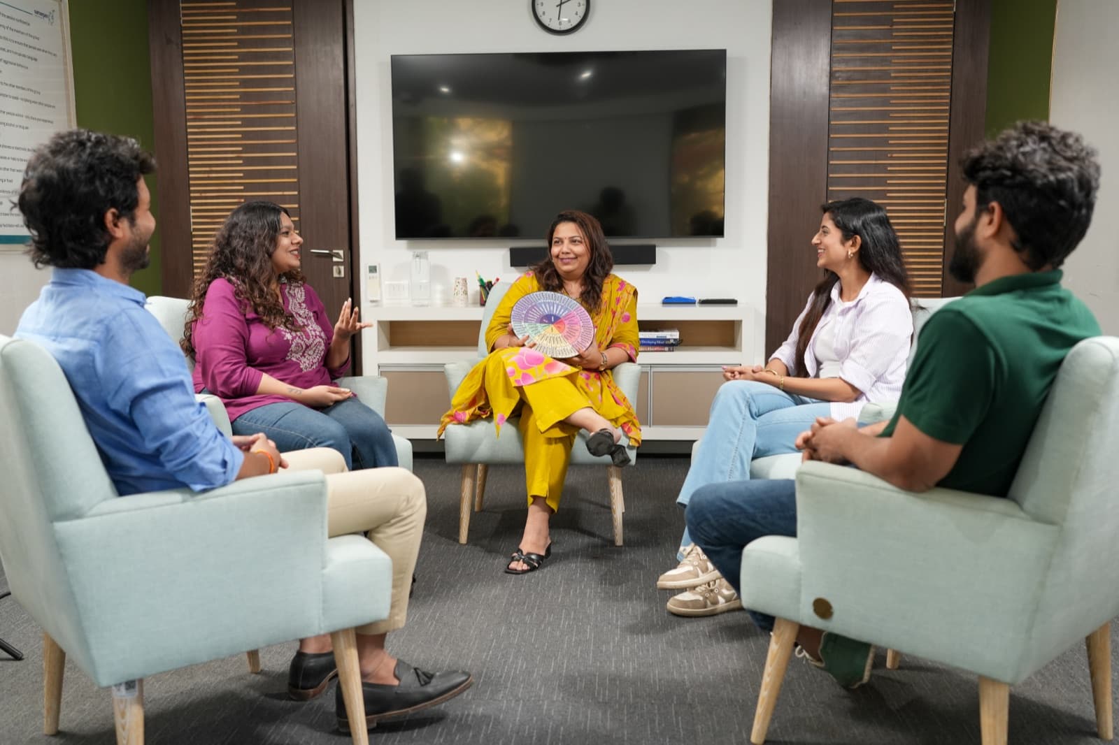 A Samarpan group therapy session — a facilitator and four participants seated in a circle of armchairs.